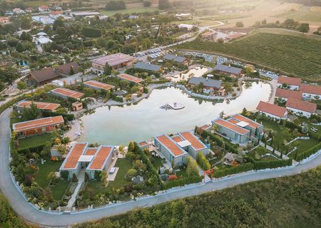 Luftbild der Chalets am Gartensee: Ein zentraler See ist von Ferienhäusern und bepflanzten Gärten umgeben.