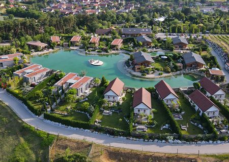 Vogelperspketive auf die Chalets am Gartensee mit üppiger Begrünung und strahlend blauem See.